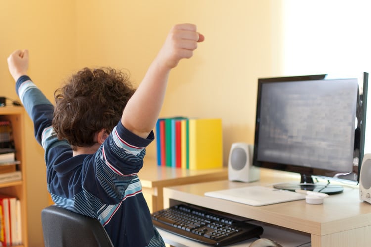 A picture of a student sitting in front of his computer at home attending a distance learning online.